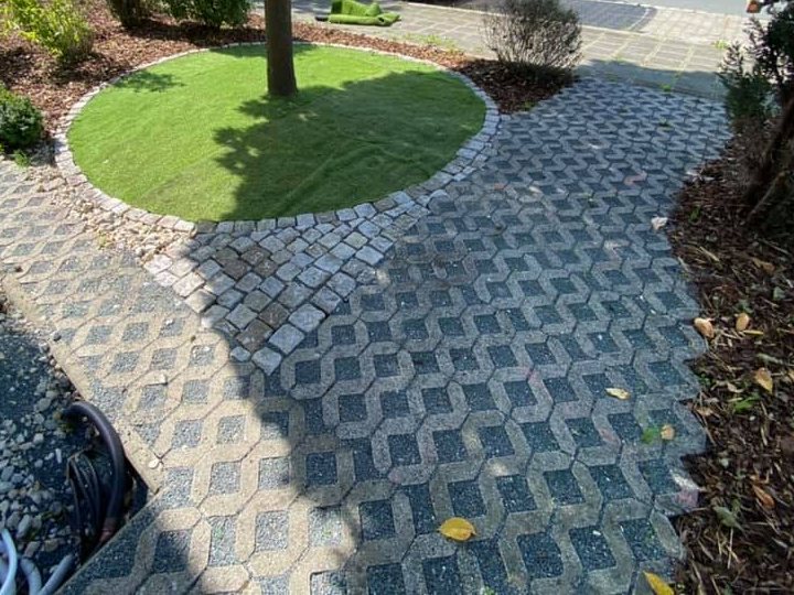 Pflasterweg um ein rundes Rasenbeet mit Baum