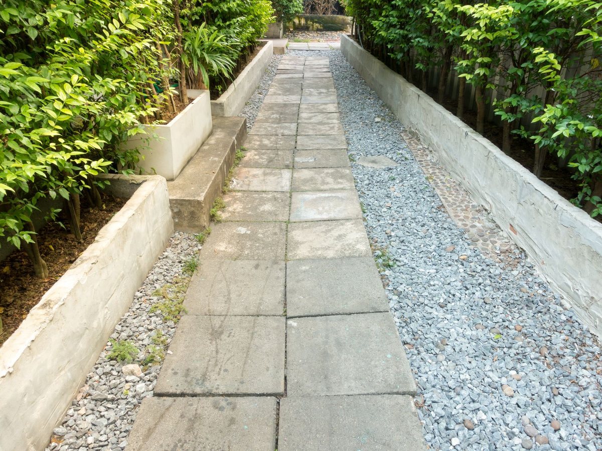 Plattenweg mit Kiesstreifen zwischen Betonbeeten