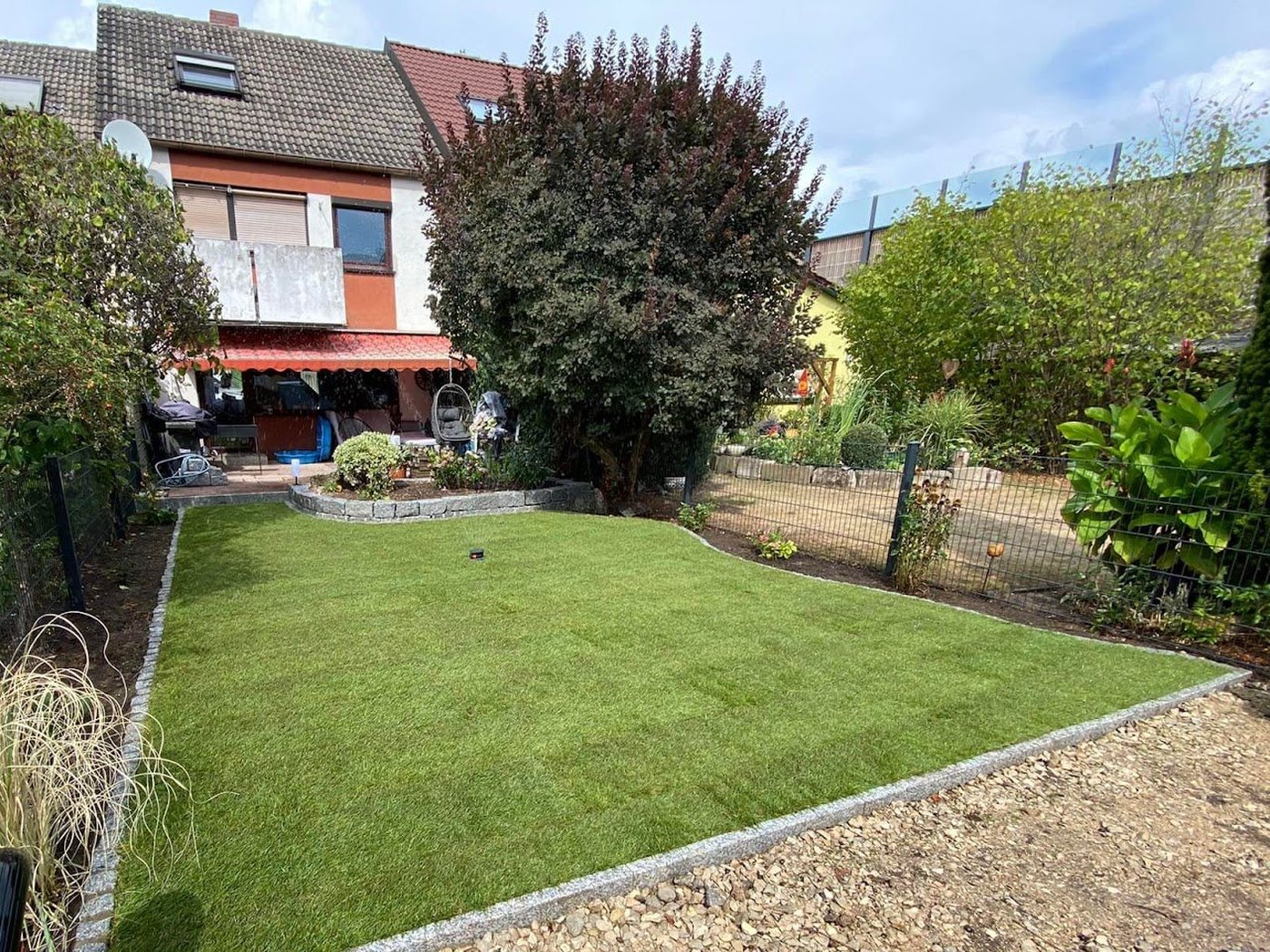 Neu verlegter Rollrasen mit Granitkante im Garten eines Reihenhauses